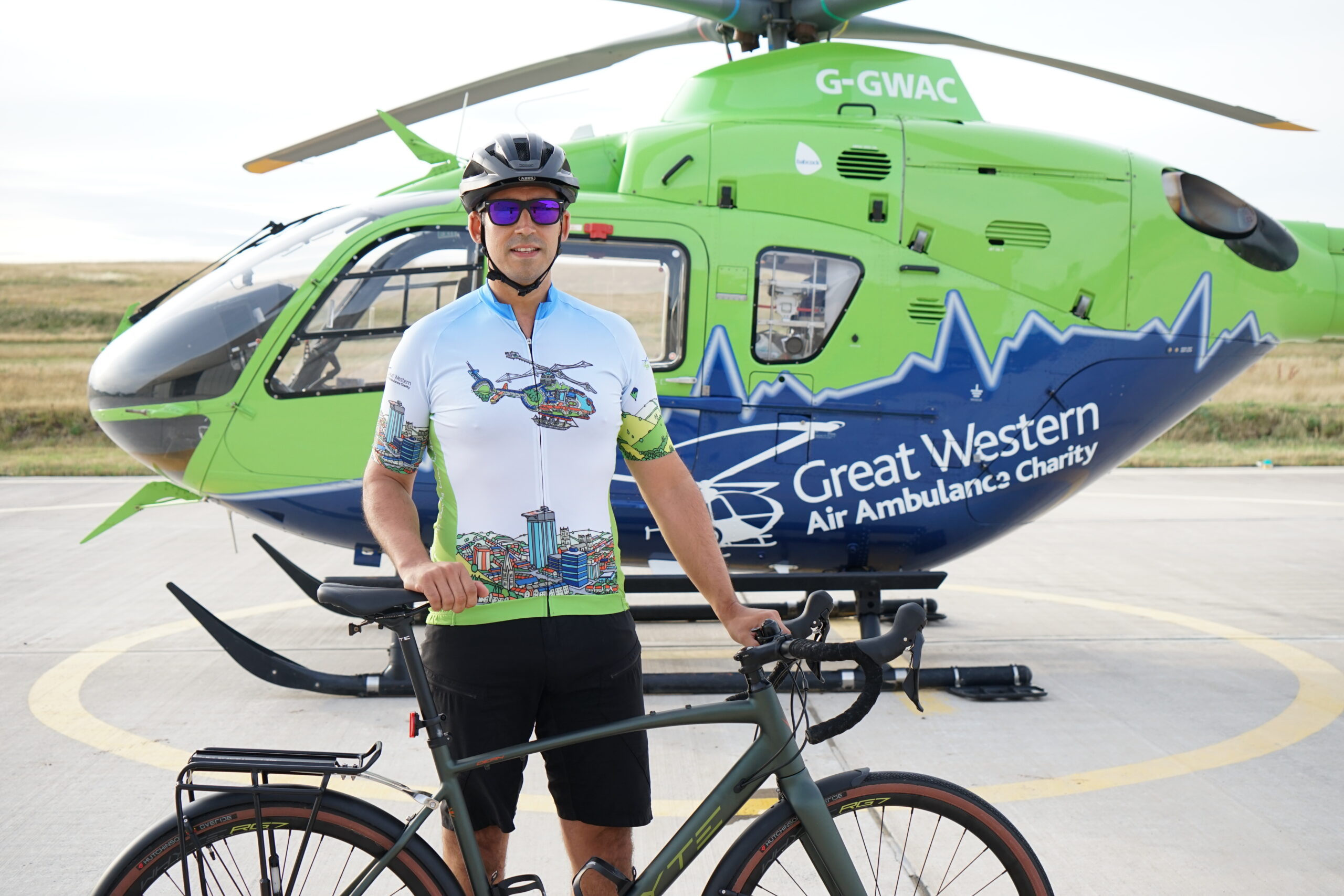 SPCC Matt in front of Helimed 65 with his bike and wearing the new GWAAC cycle jersey