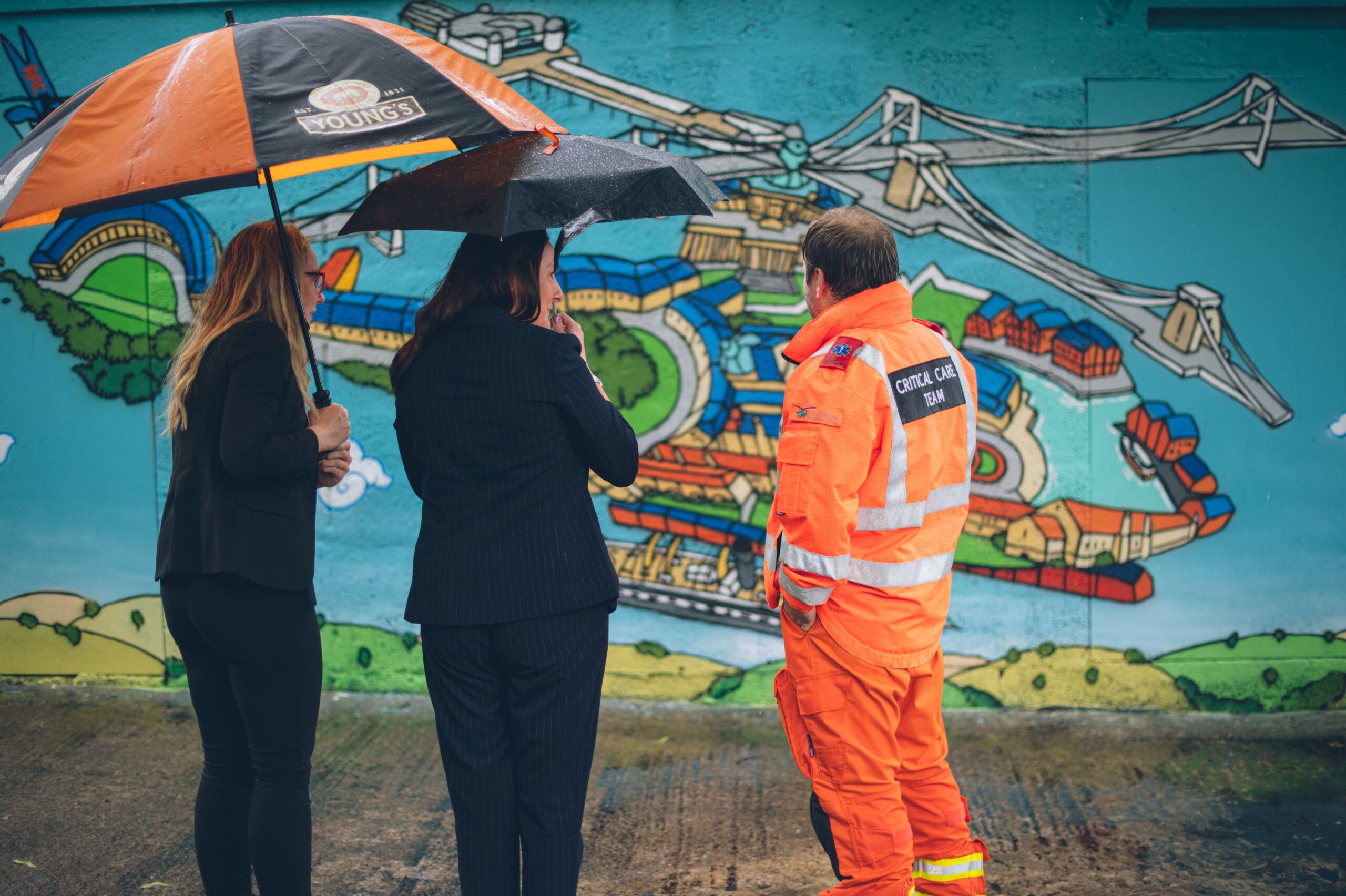Dr Andrew Heavyside and members of the Crest Hotels Group talk in front of the mural