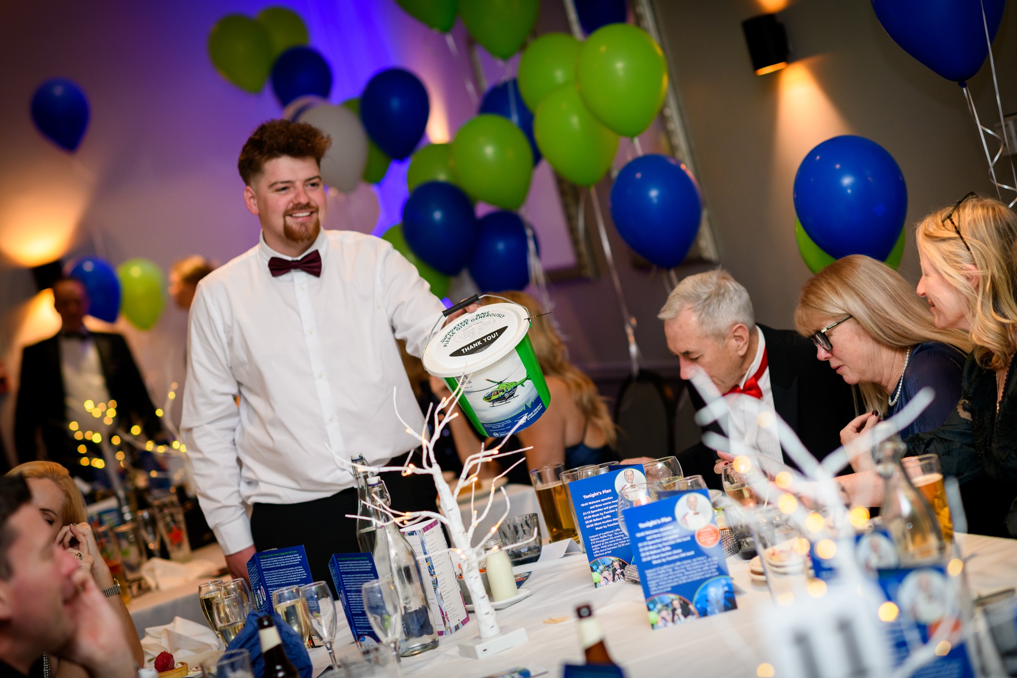 A young man in a bow-tie holding a GWAAC collection bucket.