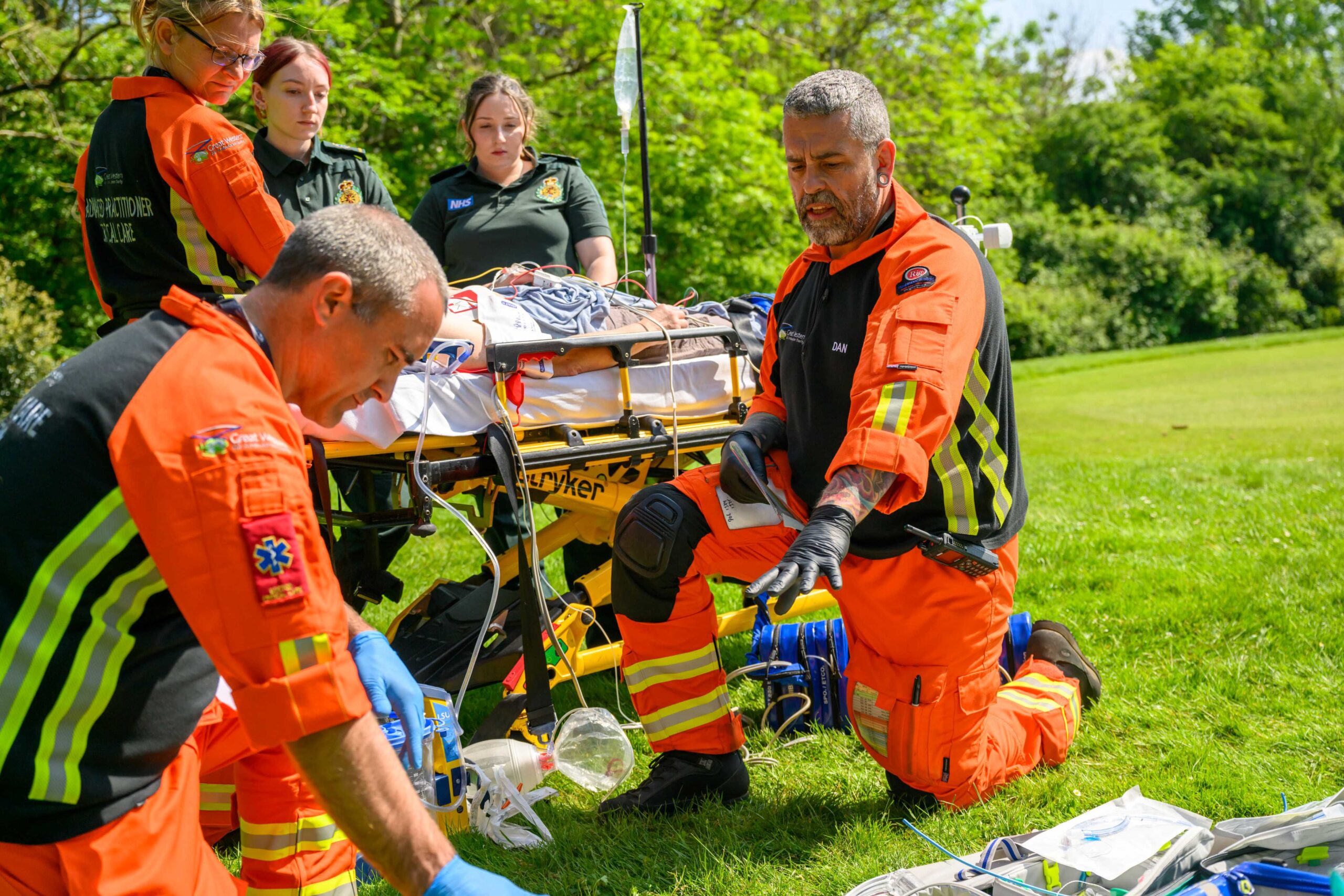 Members of the Great Western Air Ambulance Charity crew treat a patient on a stretcher with ambulance crew helping (simulation)