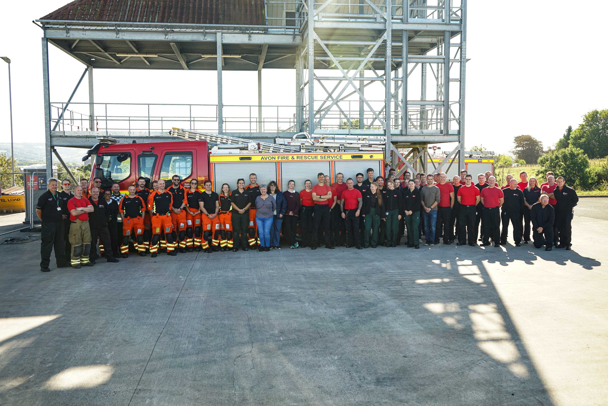 Members of Avon Fire and Rescue Service, Great Western Air Ambulance Charity and UWE students pose for a photo in front of a fire engine at Hicks Gate Fire Station