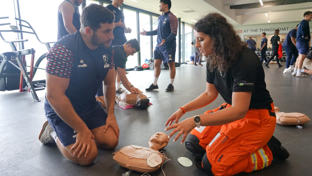 SPCC Fleur teaches a Bristol Bears rugby player how to use an AED