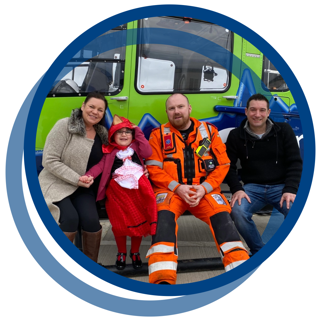four people sitting in front of a helicopter