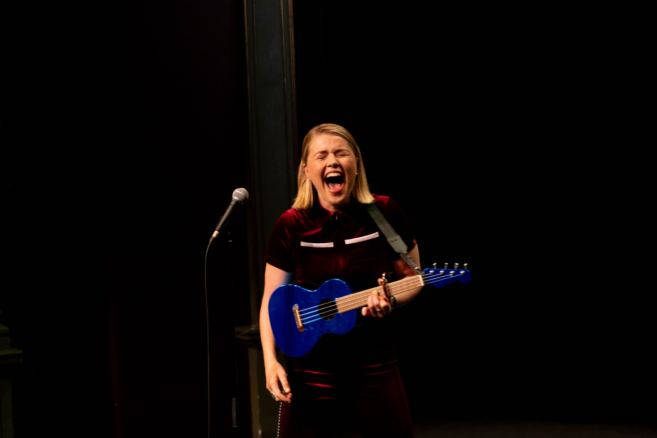 Comedian Abi Carter-Simpson laughs heartily while holding her ukelele at Heli Laughs 2023 at The Old Vic Bristol