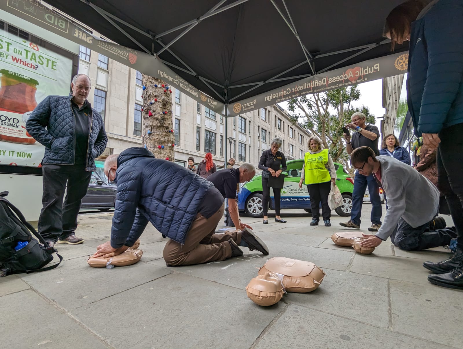 Members of the public learning to do CPR on resuscitation dummies outside the GWAAC charity shop in Gloucester city centre