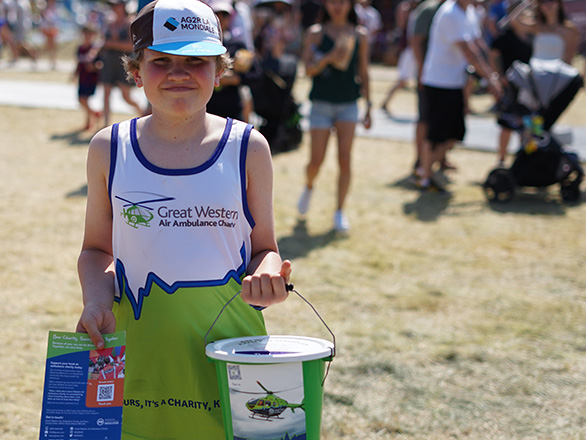 a young person in a GWAAC running vest hopding a bollection bucket and flier