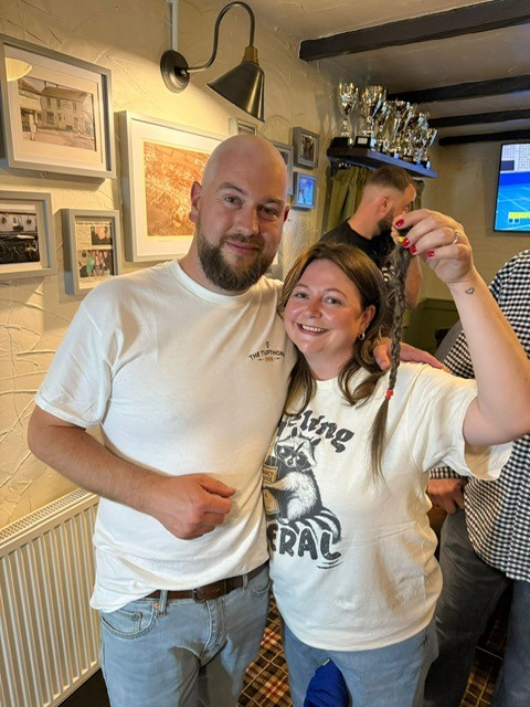 Pub landlord Jack pictured with a lady who is holding his hair after he's had it shaved off. He is bald in the image