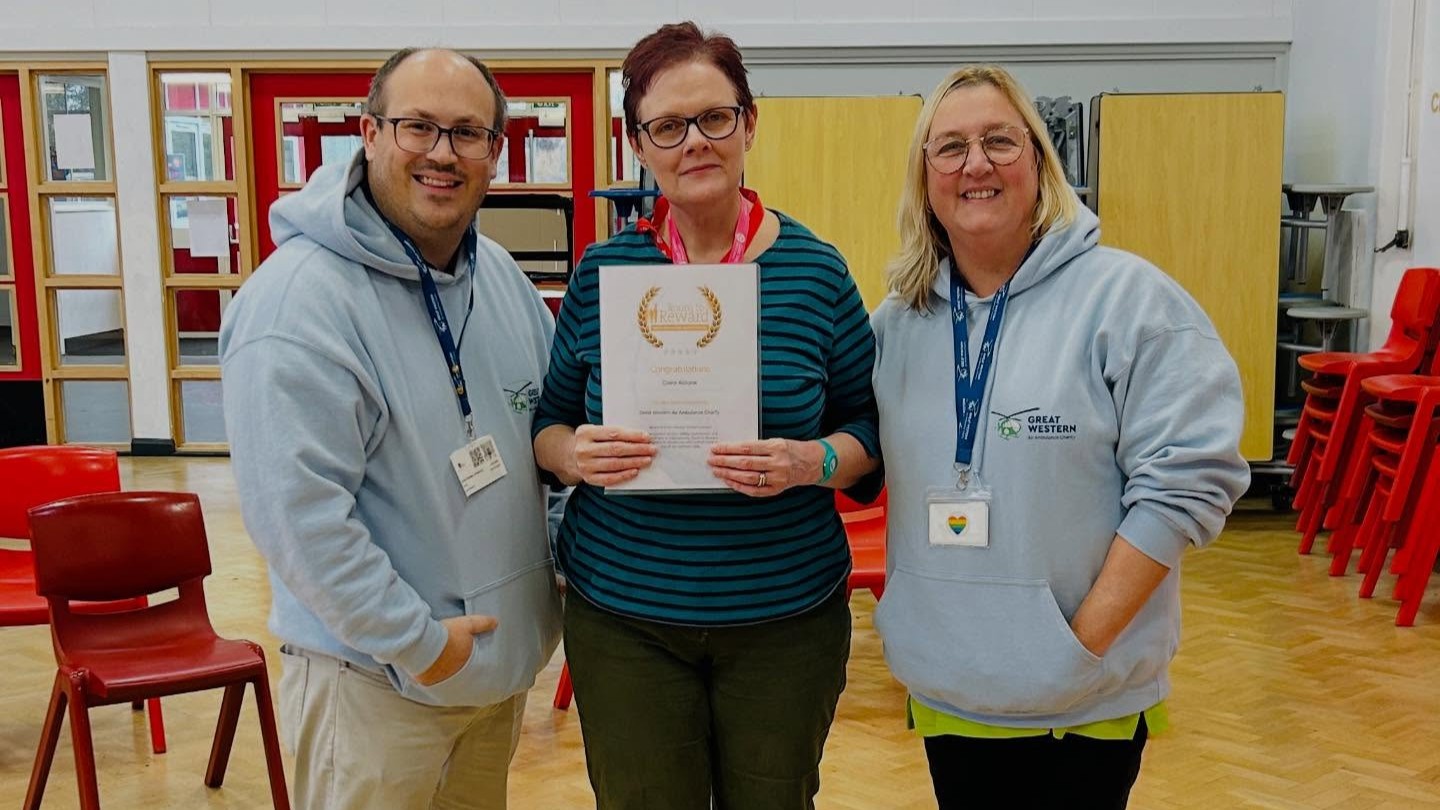 Claire poses with her certificate alongside GWAAC staff members Dan and Kate in a school hall.