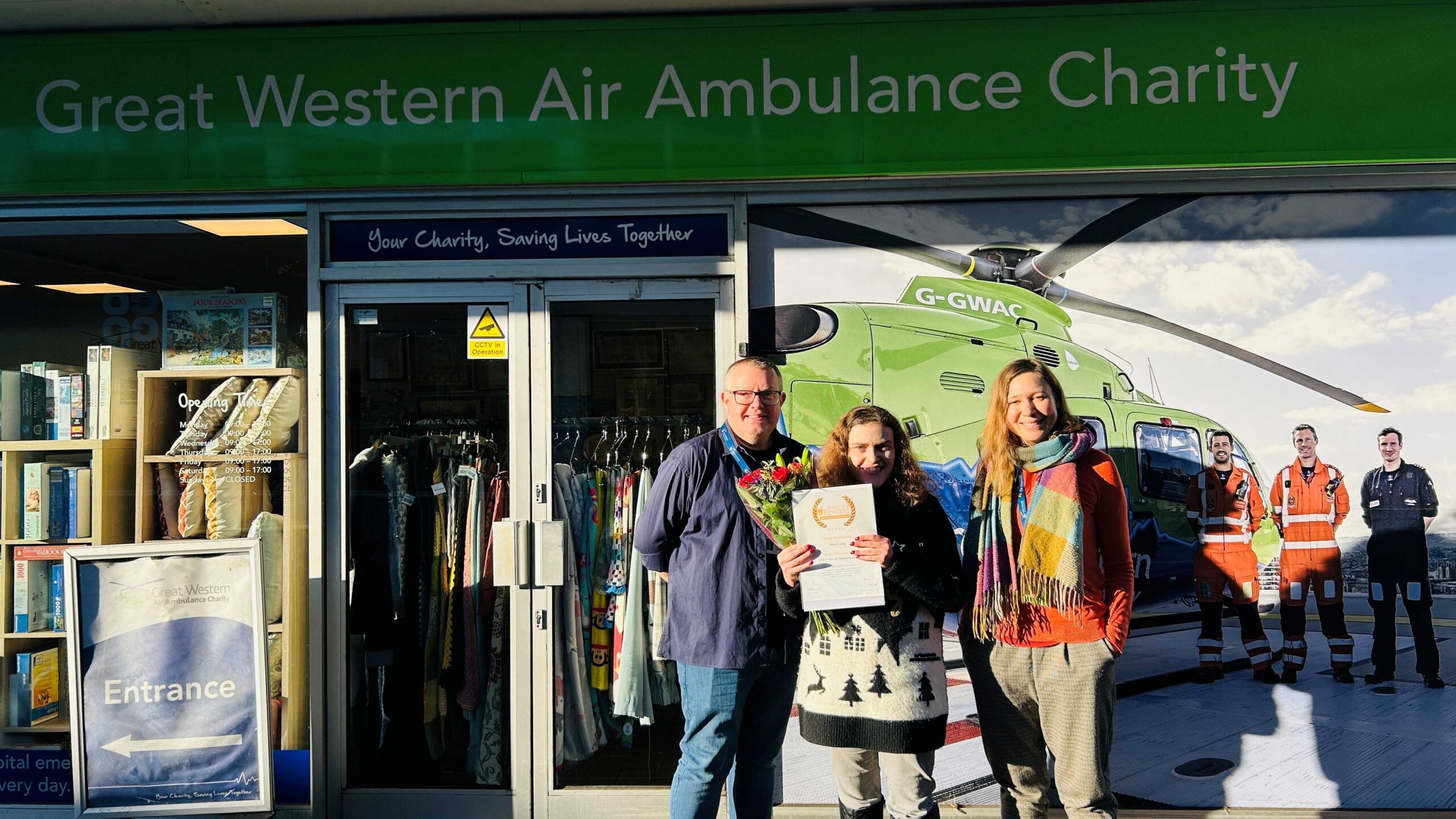 Joanna poses with her certificate outside the Westbury-on-Trym shop alongside GWAAC staff Katie and Stewart