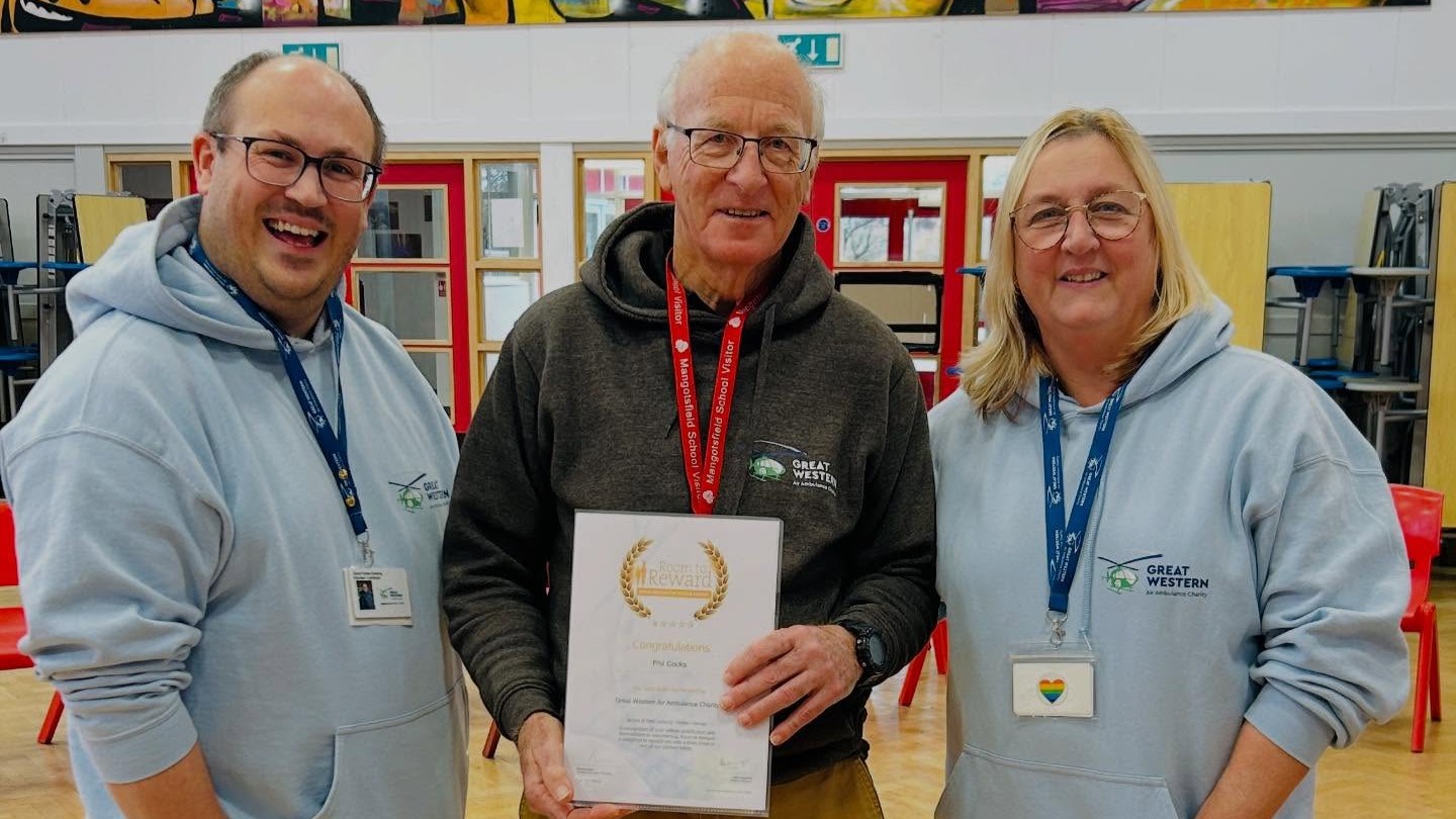 Phil poses with her certificate alongside GWAAC staff members Dan and Kate in a school hall.