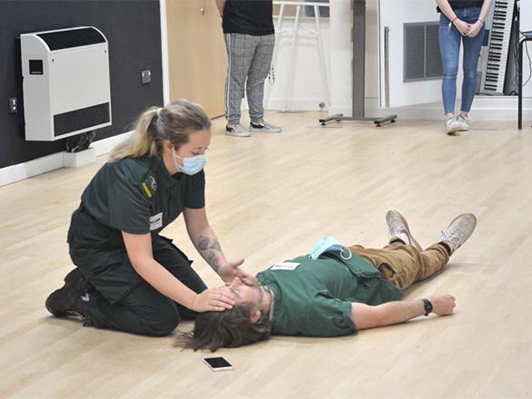 A volunteer in SWASfT uniform demonstrating how to check if someone is breathing