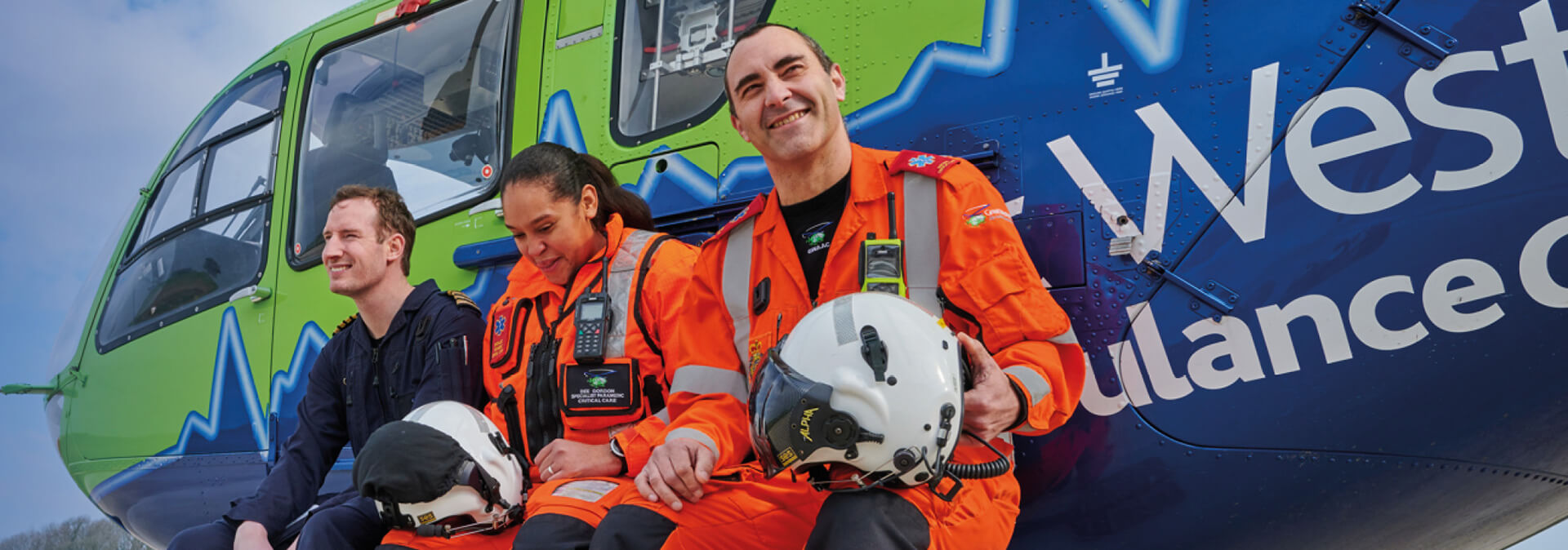 A GWAAC pilot, paramedic and doctor sat on the side of the helicopter