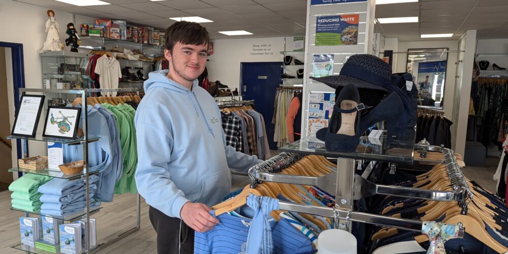 Retail volunteer Luke sorting organising clothing rails on the shopfloor