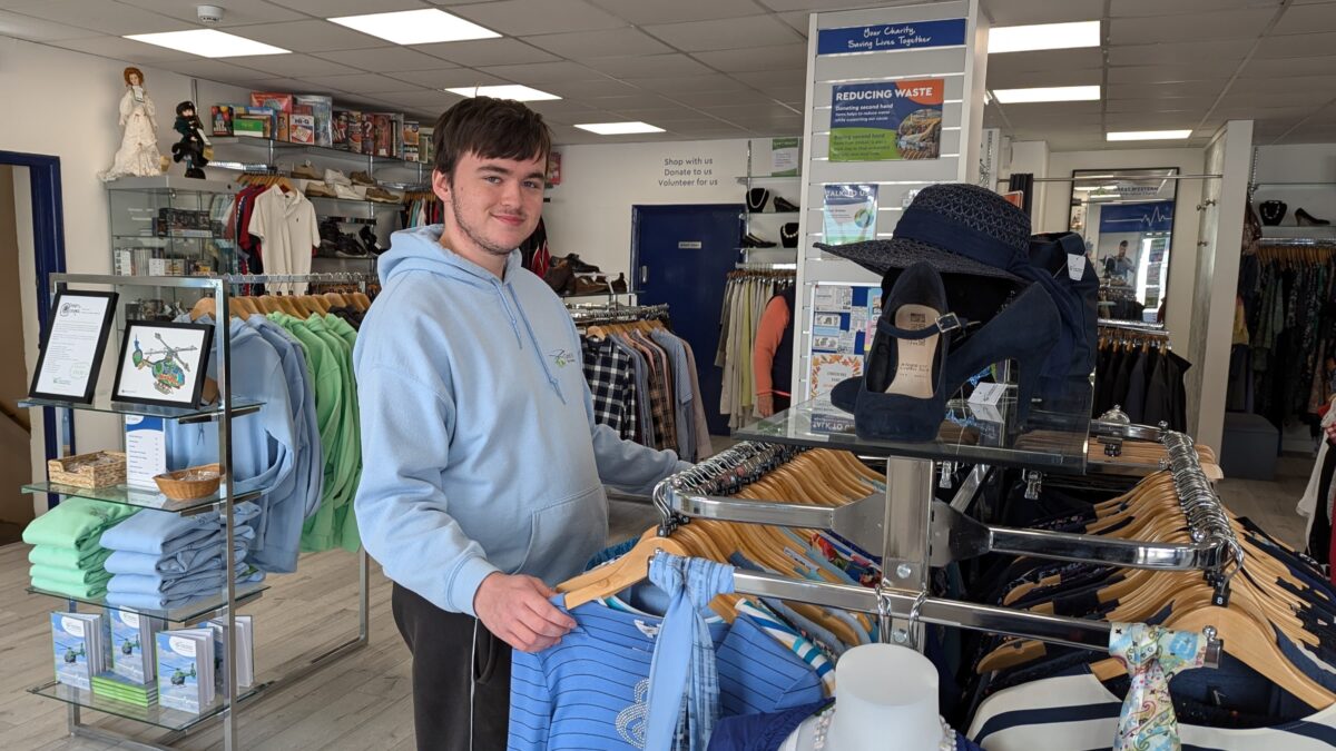 Retail volunteer Luke sorting organising clothing rails on the shopfloor