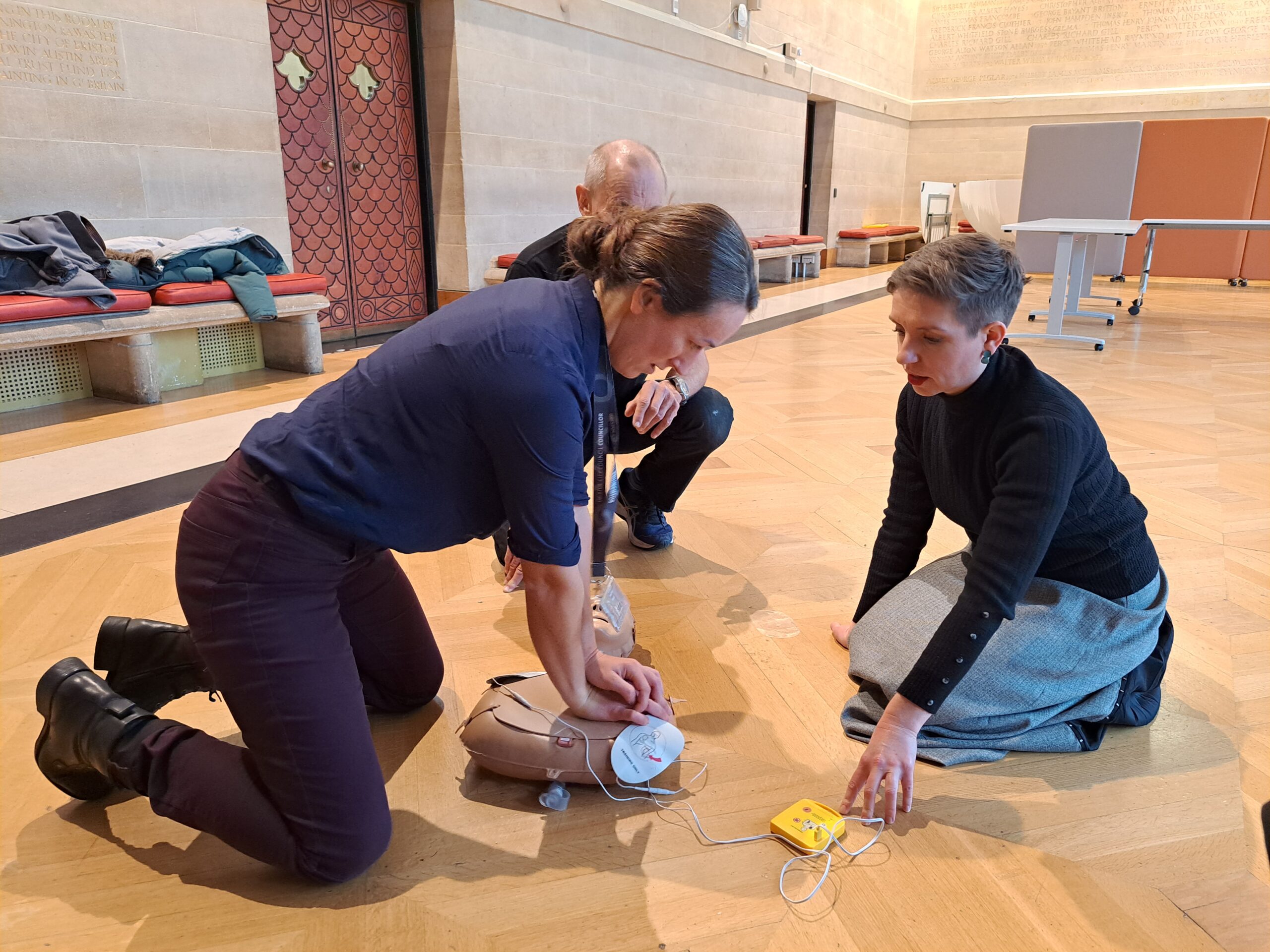 A Heartstarters volunteer teaching a Bristol City Councillor chest sompressions.