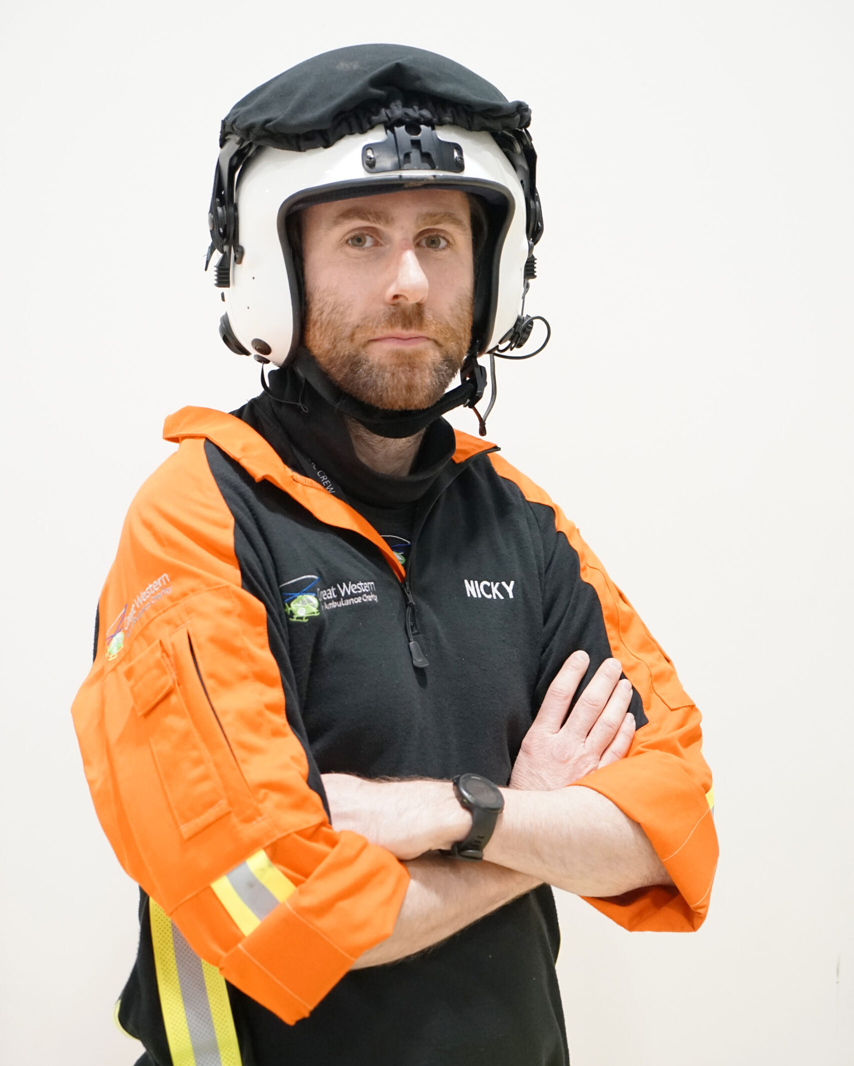 Trainee Critical Care Doctor Niky Moore poses in uniform and flight helmet, with arms crossed