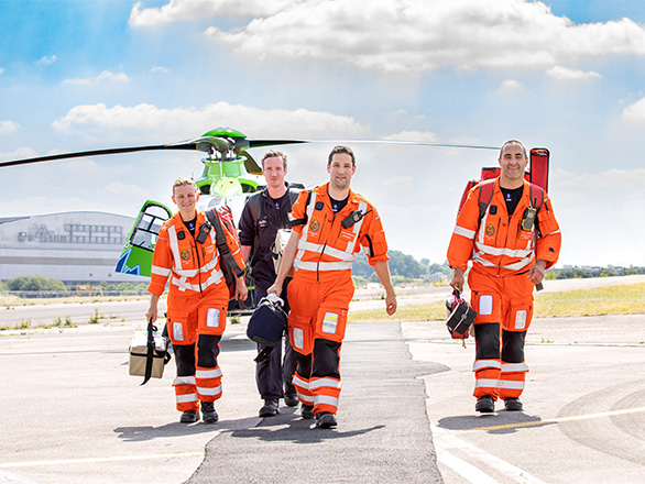 The GWAAC Critical Care Team walking away from the green and blue helicopter